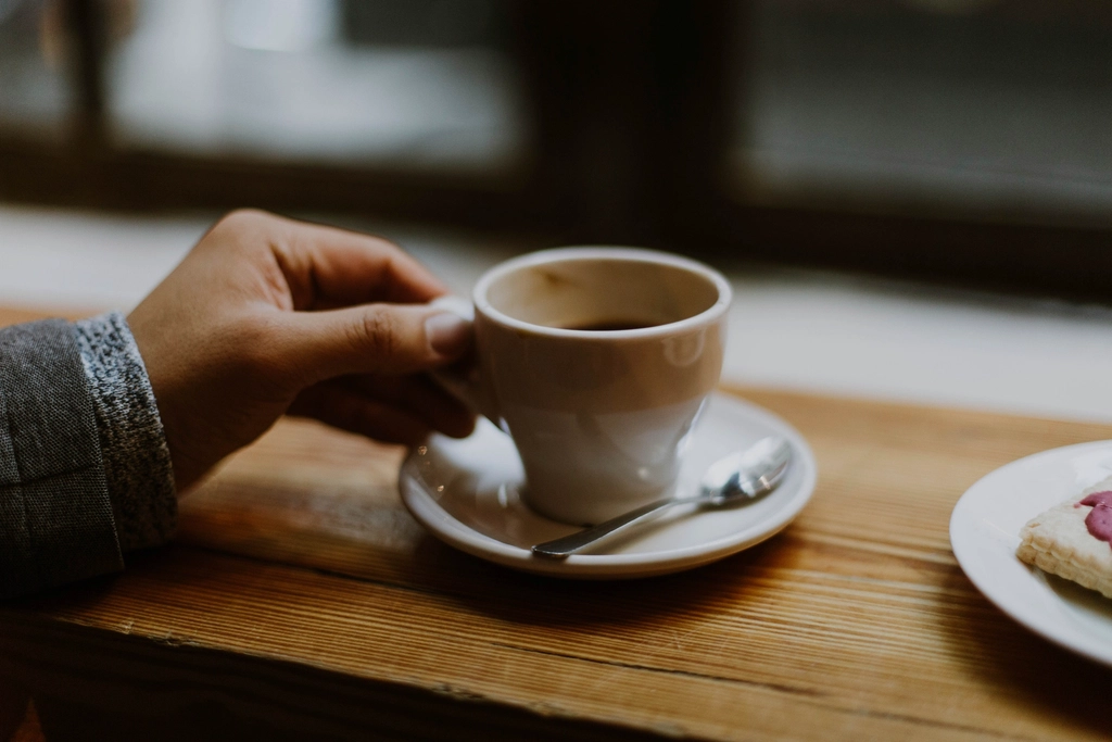 person lifting cup coffee saucer